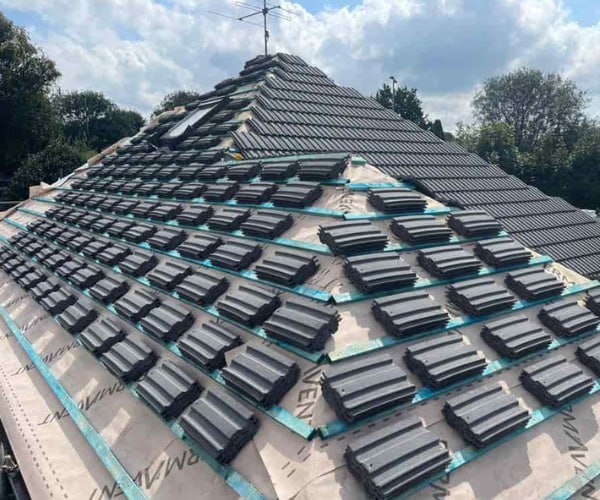 This is a photo of a new hip roof being installed. New felt, battens, and grey tiles have been installed, also a new velux window. Works carried out by UG Roofing Hemsworth